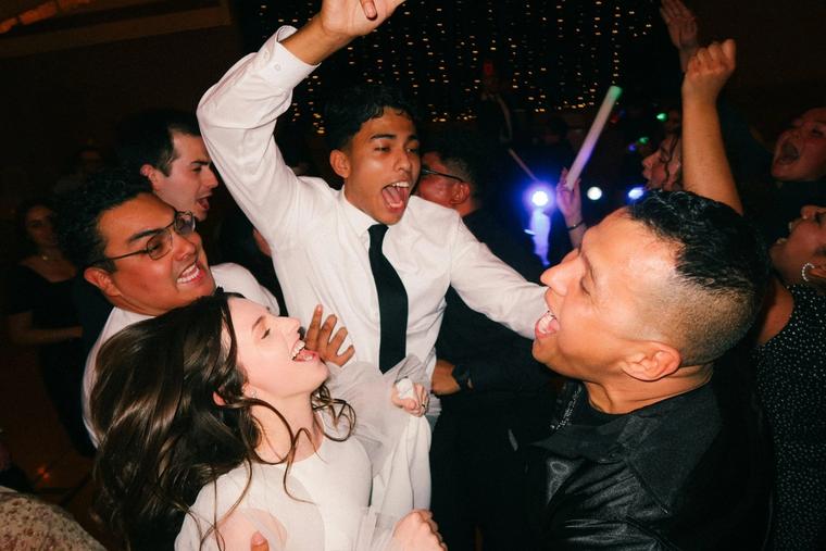 Wedding guests singing and dancing under the lights at the reception