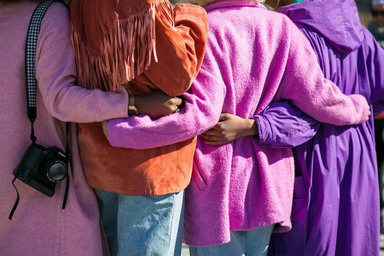 Friends in bright coats with their arms around each other