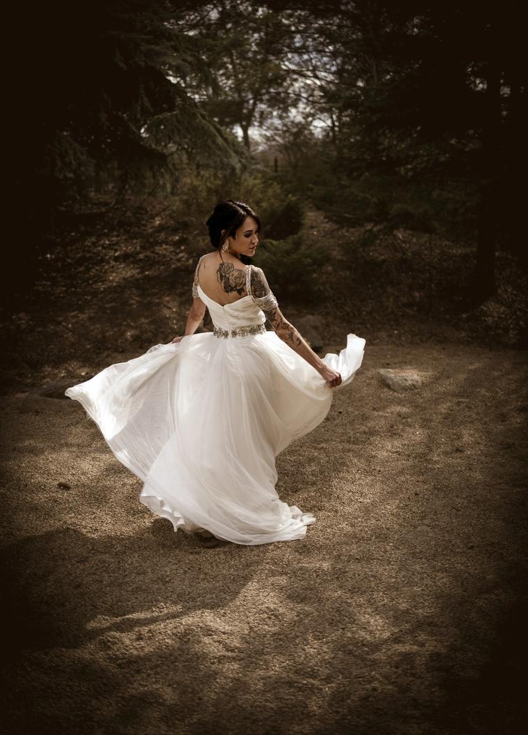 Bride twirling her gown on a woodland path
