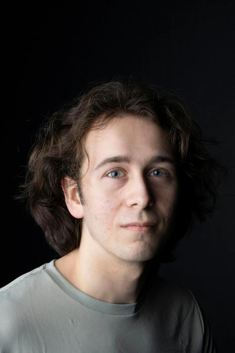Studio headshot of a young man against a dark background
