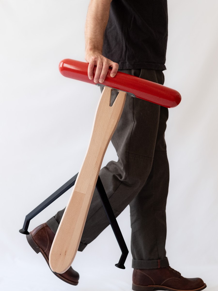 Würstelhocker by NOEMAR — sausage-shaped stool balanced on a wooden fork base. Wiener Norm collection, 2026 (view 6 of 9).