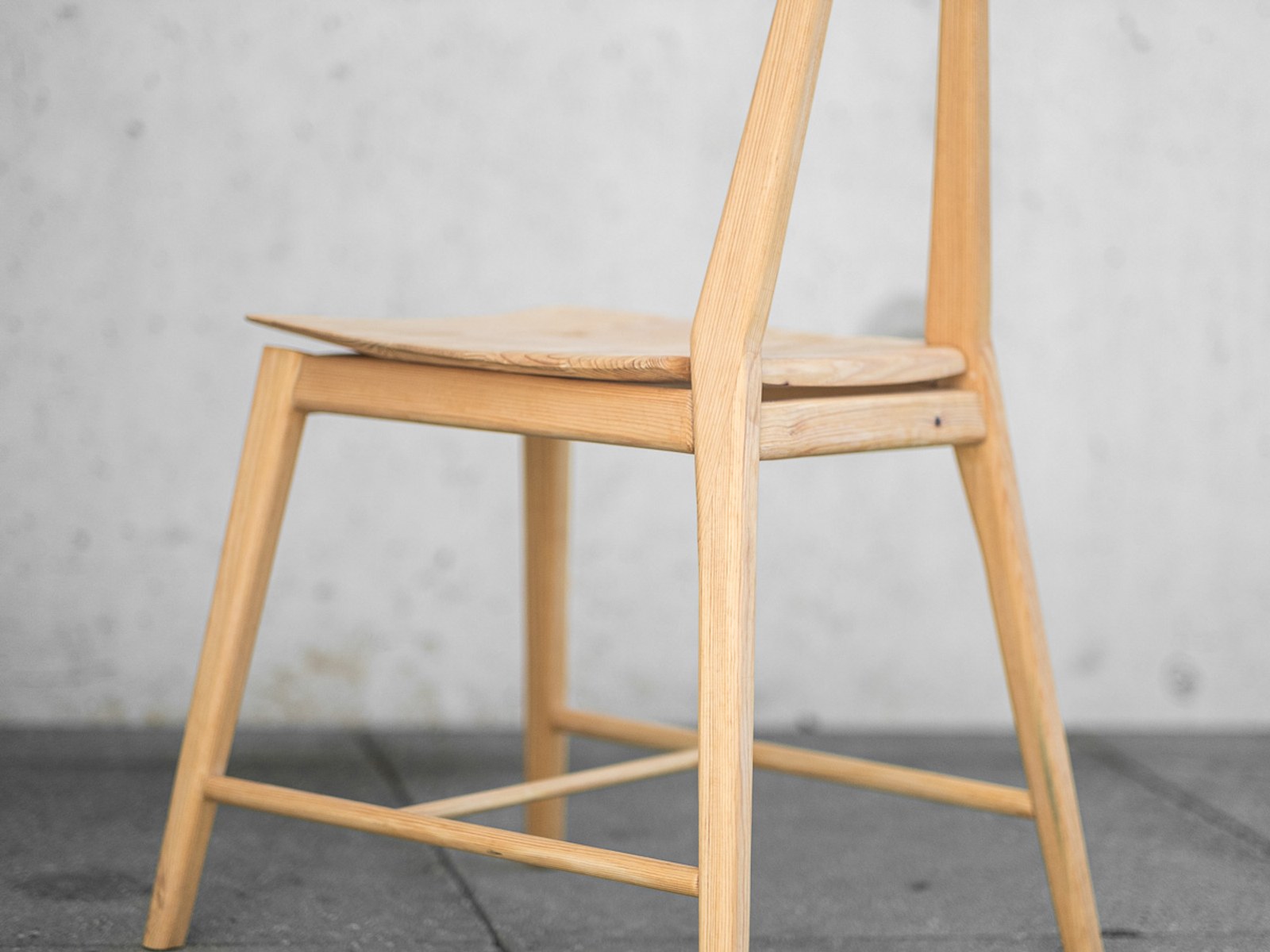 Ryoku — detail of the seat and rear legs against a concrete wall.