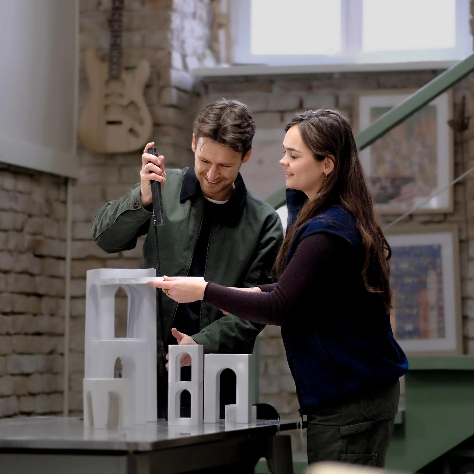 Marcel and Noelani examining an architectural model together at the studio table.