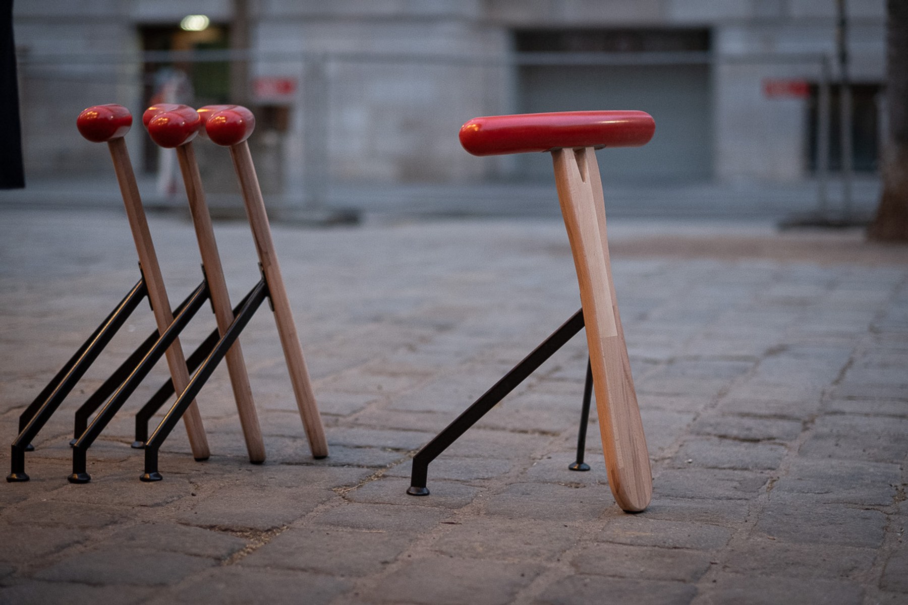 Würstelhocker by NOEMAR — sausage-shaped stool balanced on a wooden fork base. Wiener Norm collection, 2026 (view 2 of 9).