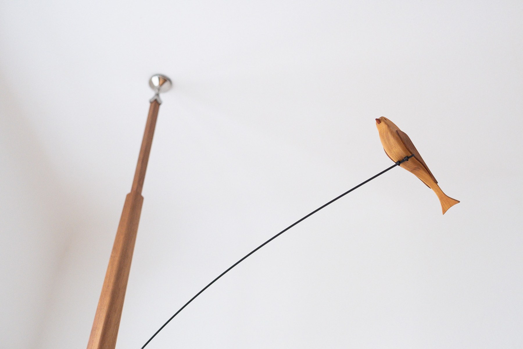 Boga by NOEMAR — tensioned floor-to-ceiling sculpture with a small bird perched at the end of its branch. Wiener Norm collection, 2026 