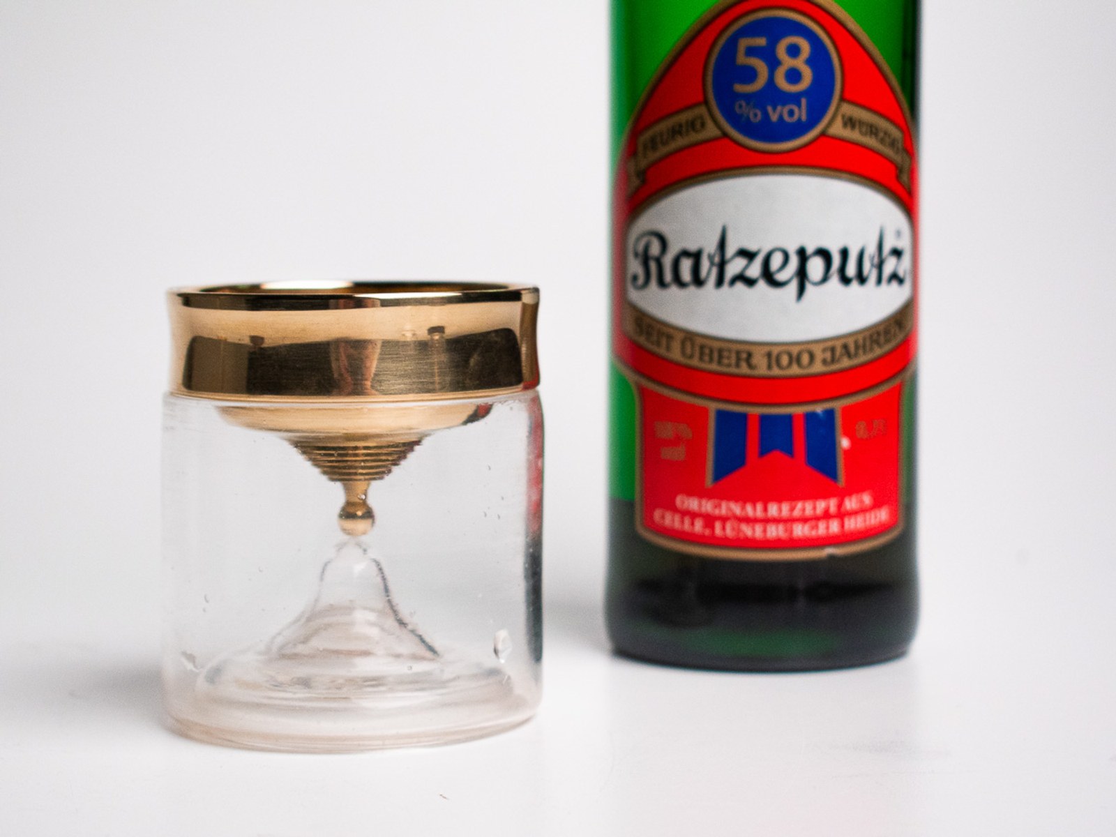 In Limbo — the brass-rimmed chalice and glass timer beside a bottle of Ratzeputz liqueur.
