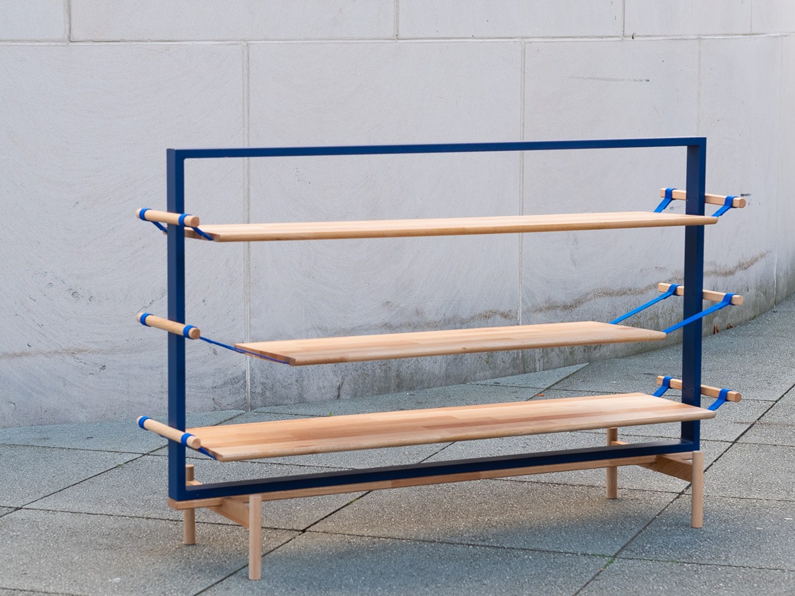 Tendere — three-quarter view of the shelf frame with wood boards suspended by webbing straps.