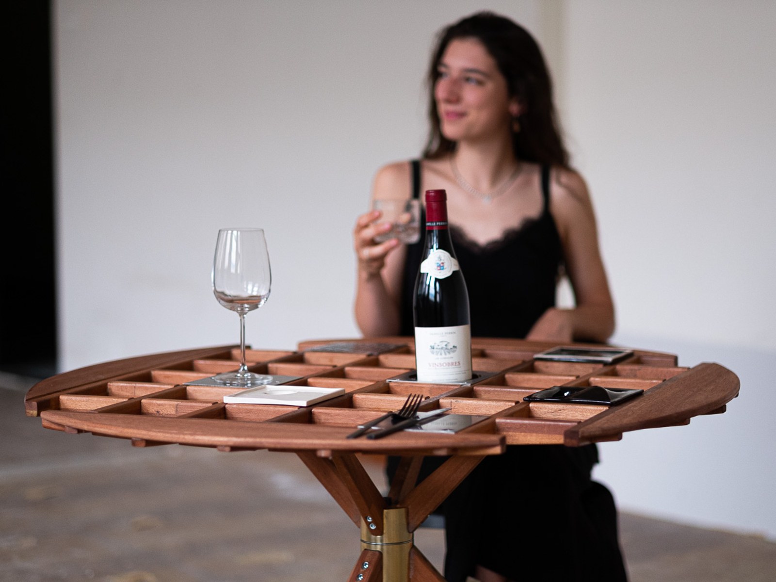 An Audience of Me — three-quarter view of the table set with wine, a diner blurred in the background.