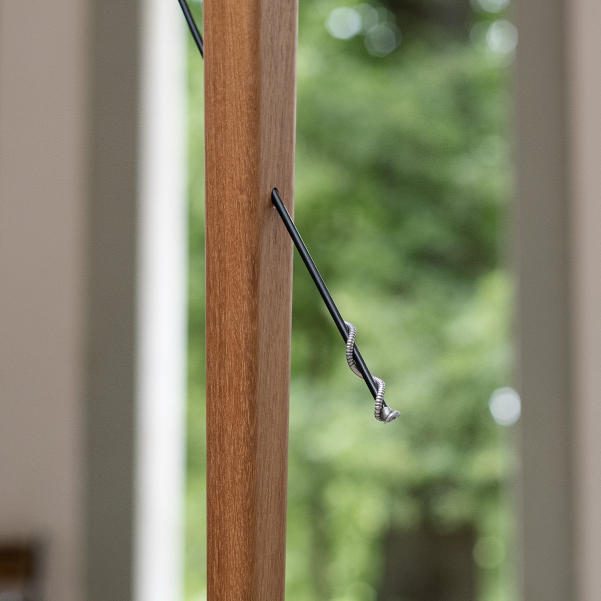 Boga by NOEMAR — tensioned floor-to-ceiling sculpture with a small bird perched at the end of its branch. Wiener Norm collection, 2026 