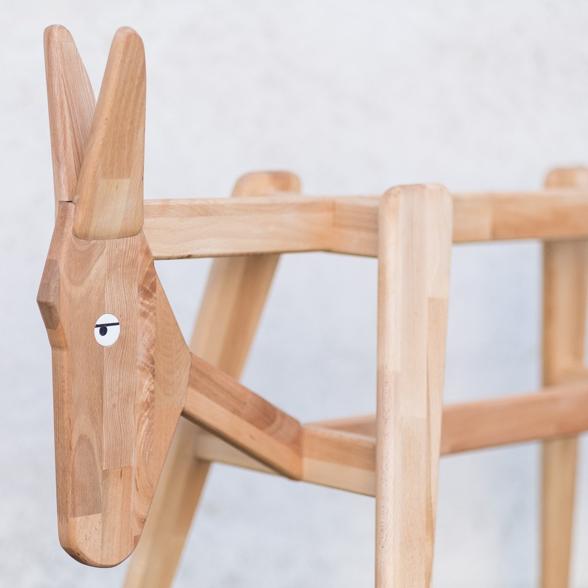Donkey by NOEMAR — detail of the frame's carved head and eye, with the cross-braced legs behind it.