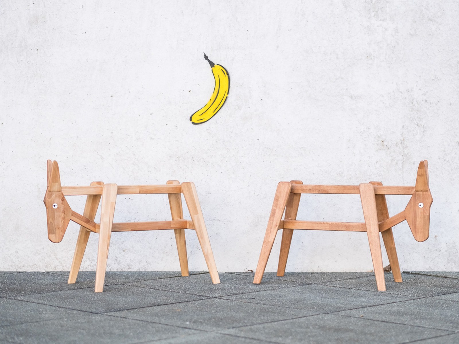 Donkey by NOEMAR — two bare frames facing each other against a concrete wall, a painted banana graphic above.