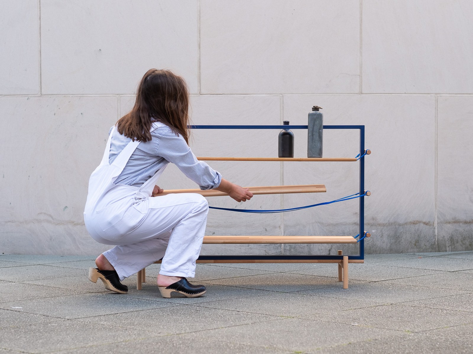 Tendere — a hand adjusting one of the suspended wood boards.