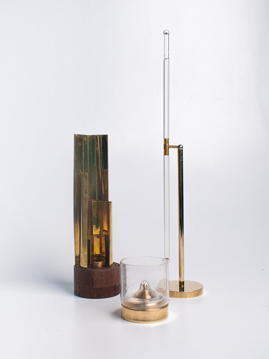 In Limbo by NOEMAR — a glass and brass chalice, a ball-drop timer, and a rotating flame lamp, the three-piece ritual set for drinking Ratzeputz.