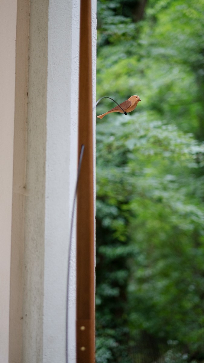 Boga by NOEMAR — tensioned floor-to-ceiling sculpture with a small bird perched at the end of its branch. Wiener Norm collection, 2026