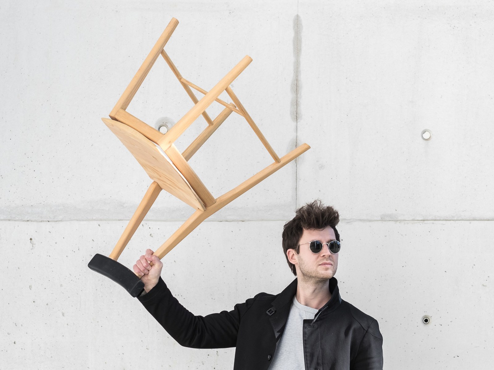 Ryoku — a person holding the chair aloft by one leg, backrest visible.
