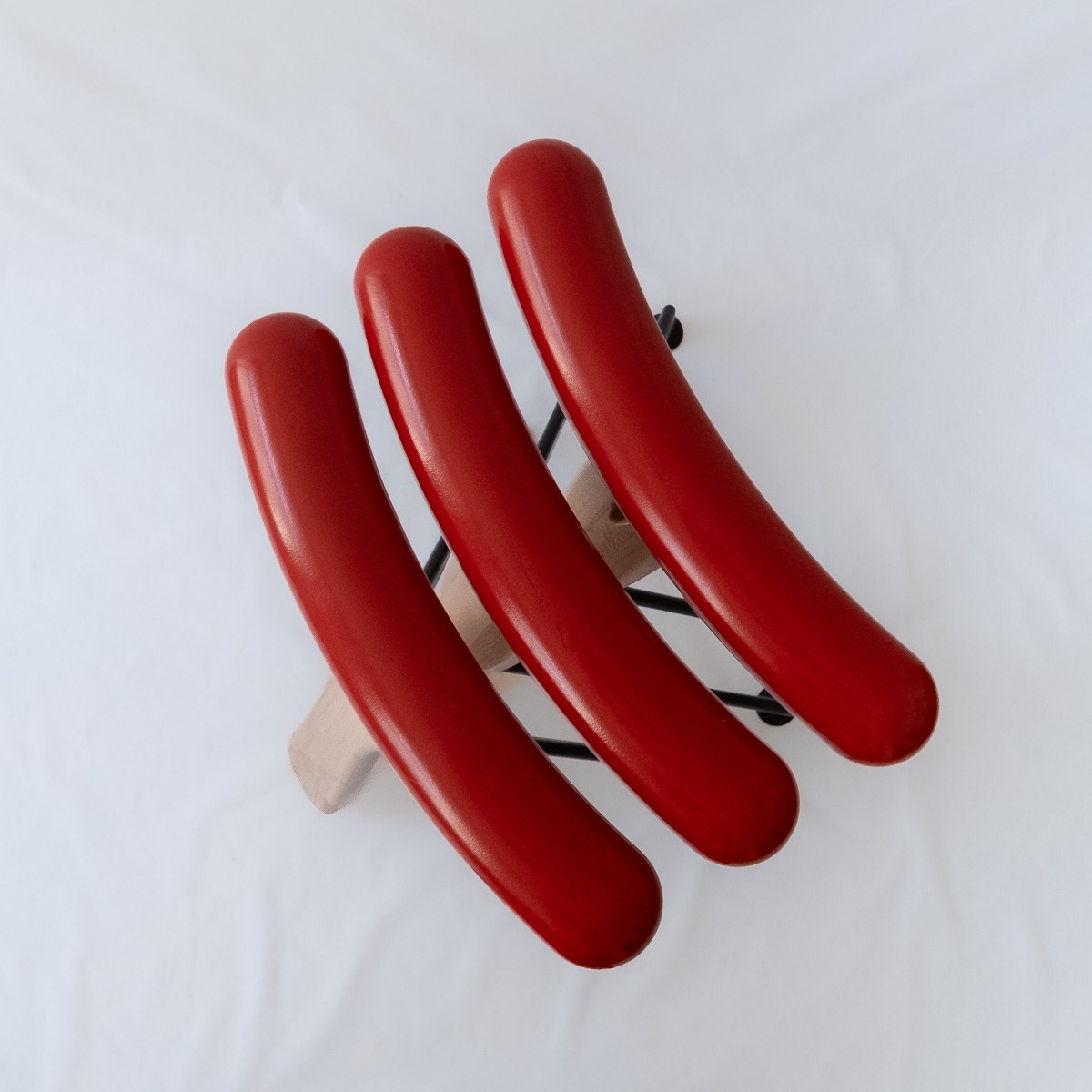 Würstelhocker by NOEMAR — sausage-shaped stool balanced on a wooden fork base. Wiener Norm collection, 2026 (view 7 of 9).