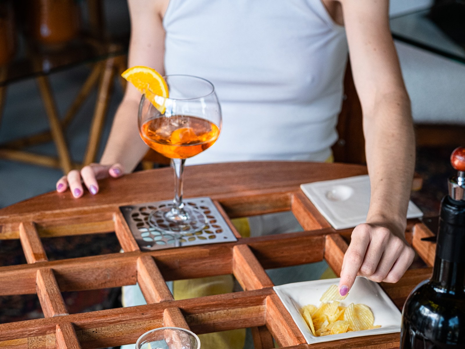 An Audience of Me — a hand placing snacks onto a ceramic dish beside a garnished cocktail.