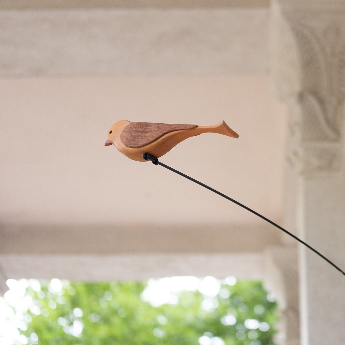 Boga by NOEMAR — tensioned floor-to-ceiling sculpture with a small bird perched at the end of its branch. Wiener Norm collection, 2026 