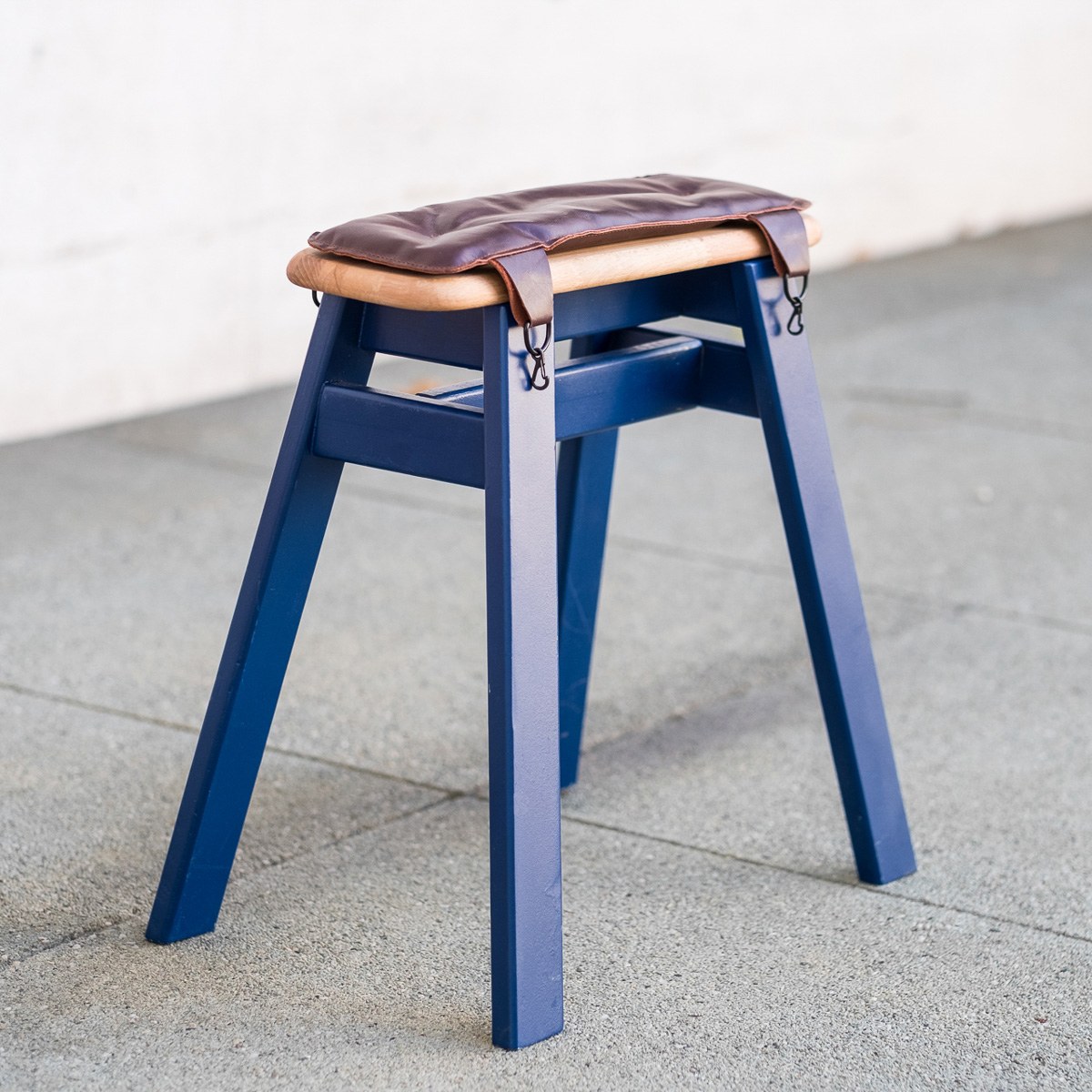 Donkey by NOEMAR — the blue stool with its padded leather seat and clip-on straps.