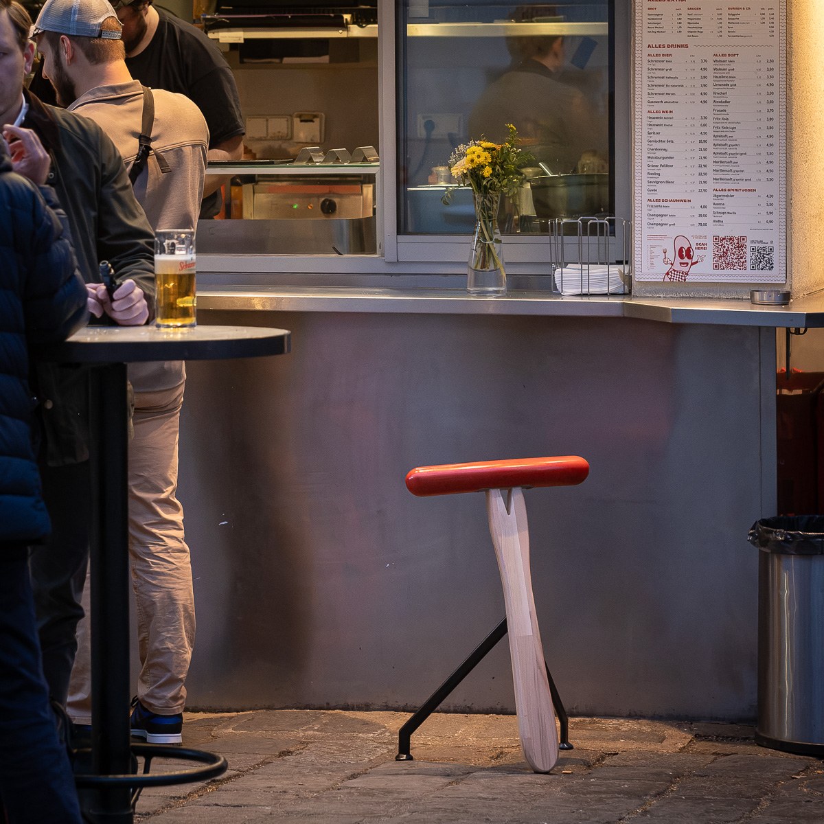 Würstelhocker by NOEMAR — a sausage-shaped stool balanced on a wooden fork base, inspired by Vienna’s Würstelstand.
