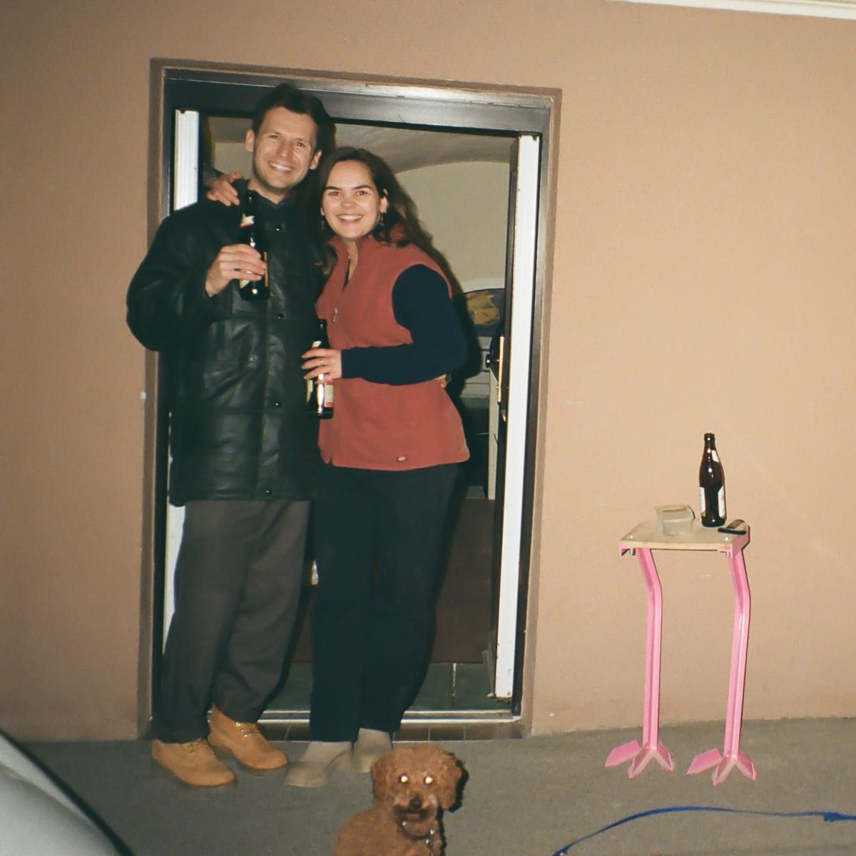 Noelani and Marcel at the studio entrance, celebrating with a drink.