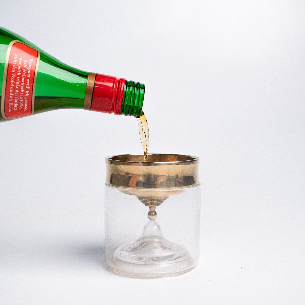 In Limbo by NOEMAR — a glass and brass chalice, a ball-drop timer, and a rotating flame lamp, the three-piece ritual set for drinking Ratzeputz.