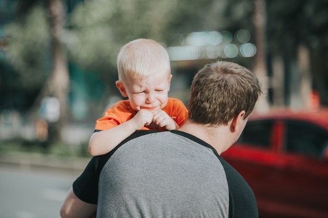 Child crying on father's shoulder