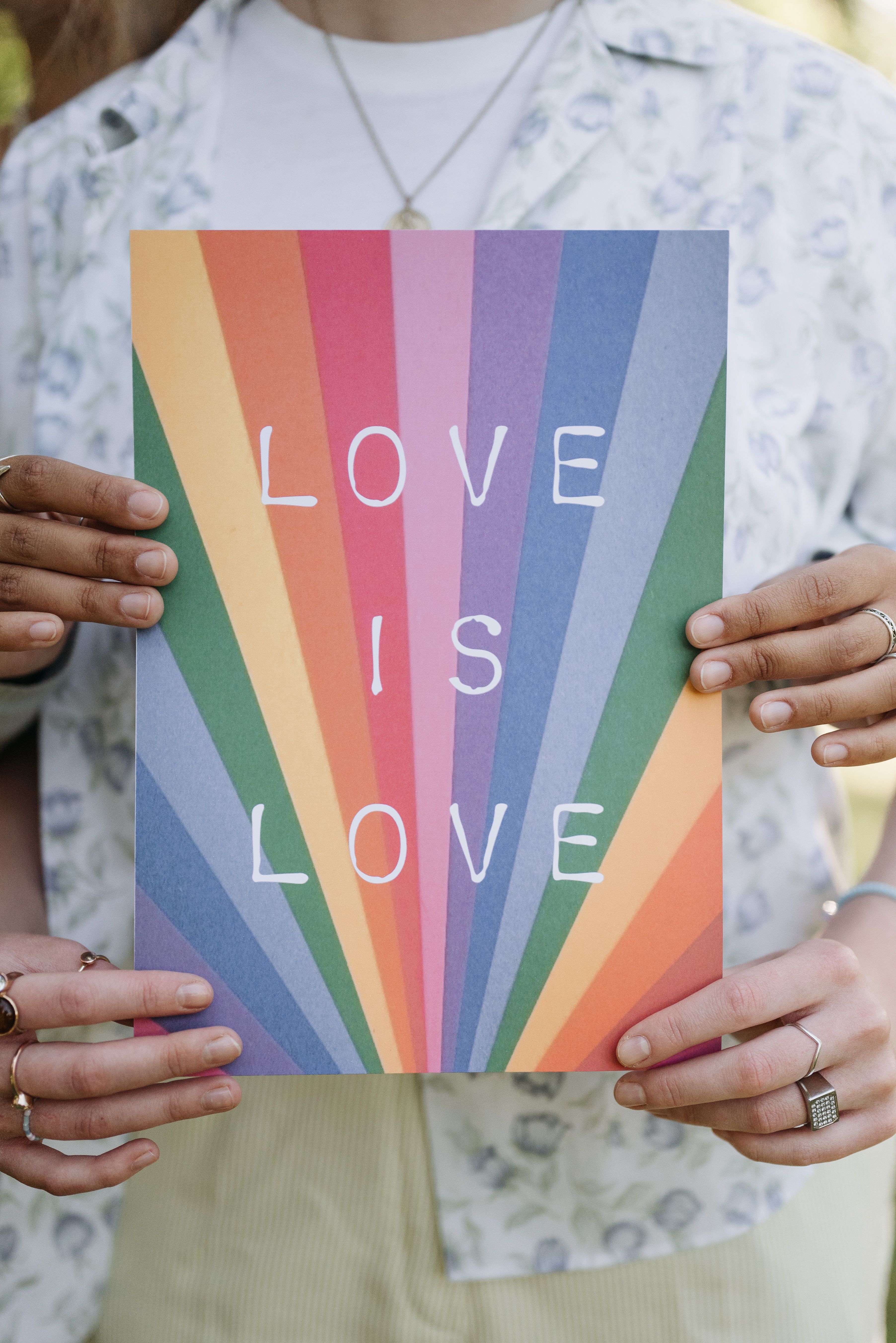 Hands holding a rainbow Love is Love poster