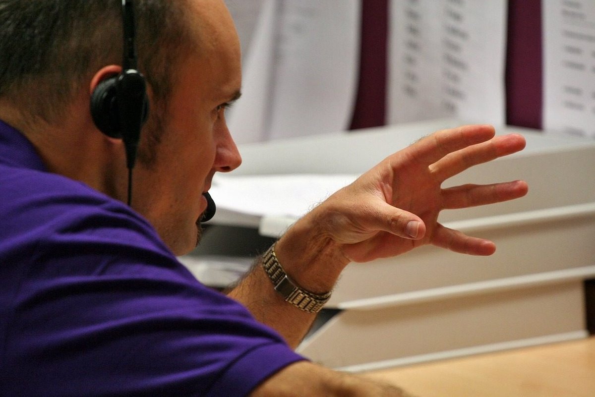 Man wearing a headset on a phone call, referring to vishing where a familiar voice can no longer be trusted