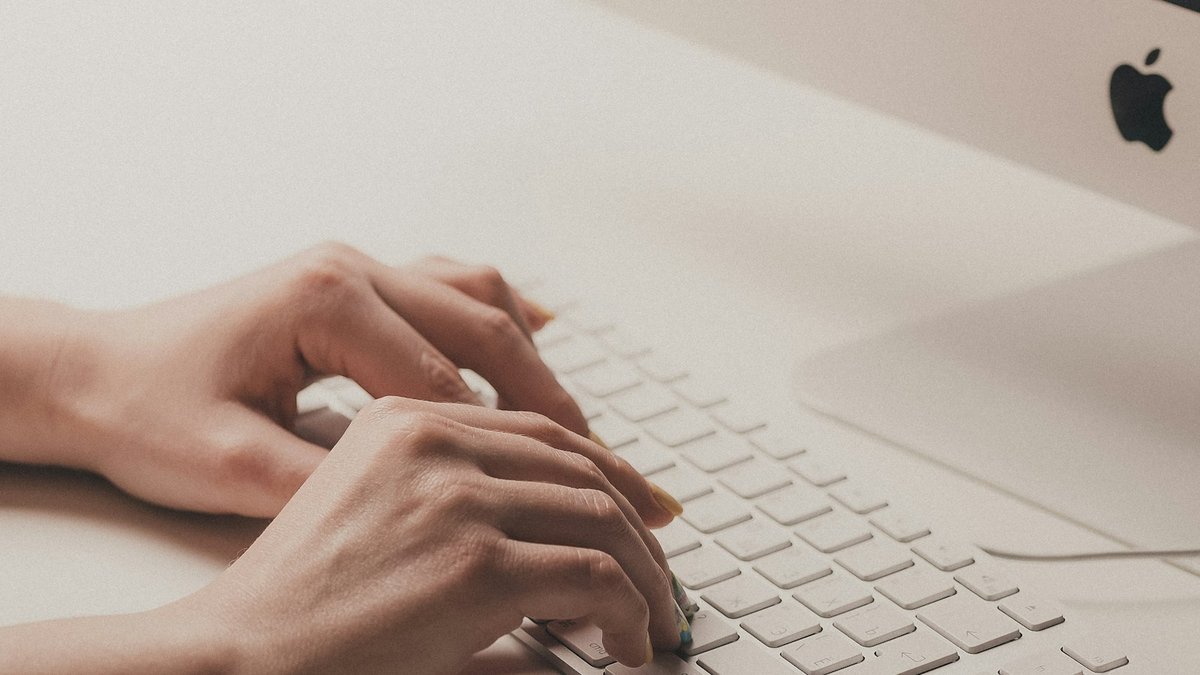 Two hands typing on a white keyboard
