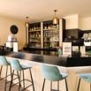 Bar lounge avec tabourets bleus et étagères de spiritueux