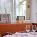 Salle gastronomique aux banquettes orange et livres d'art