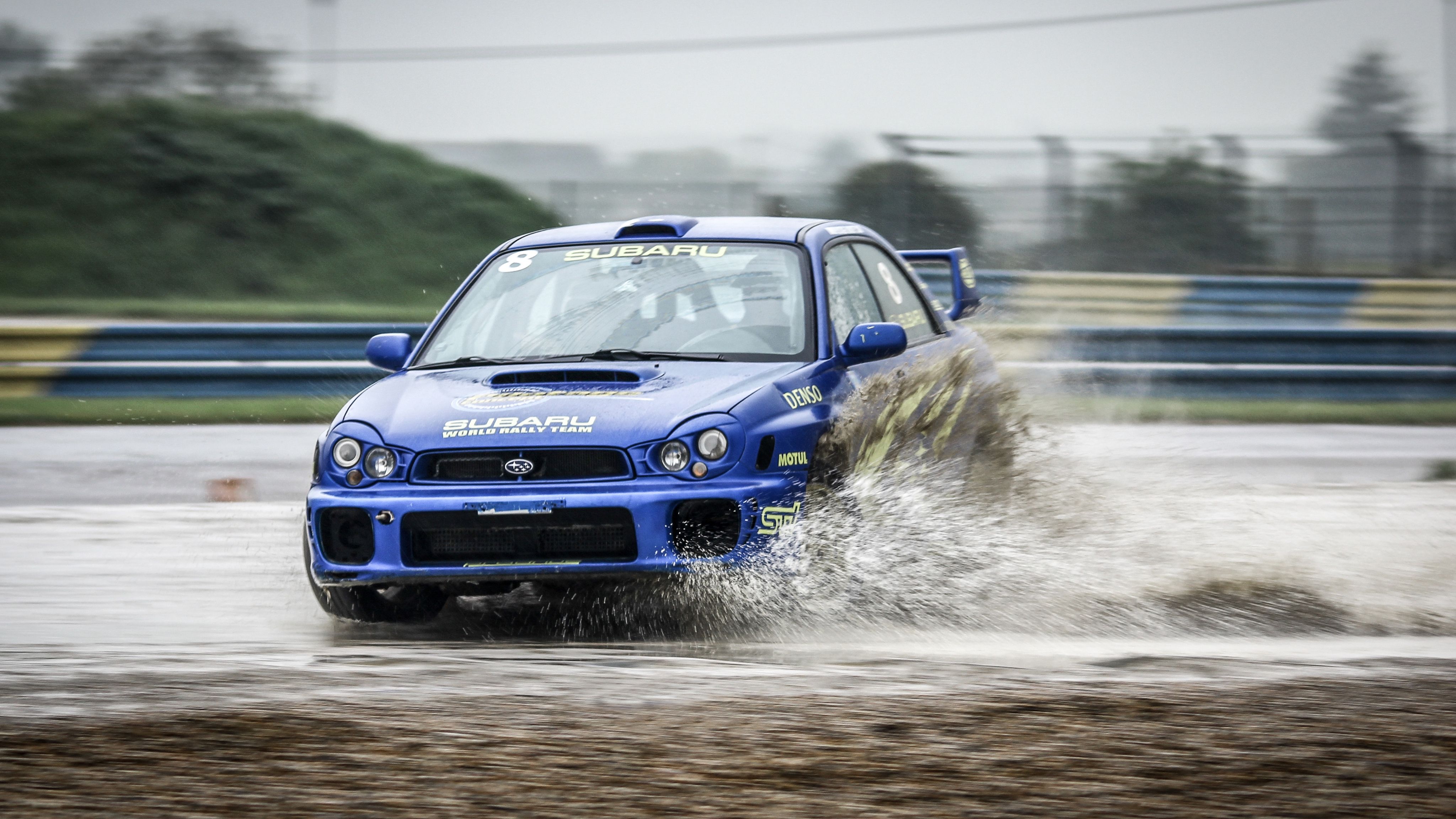 Subaru Impreza bleue éclaboussant la flaque pluie