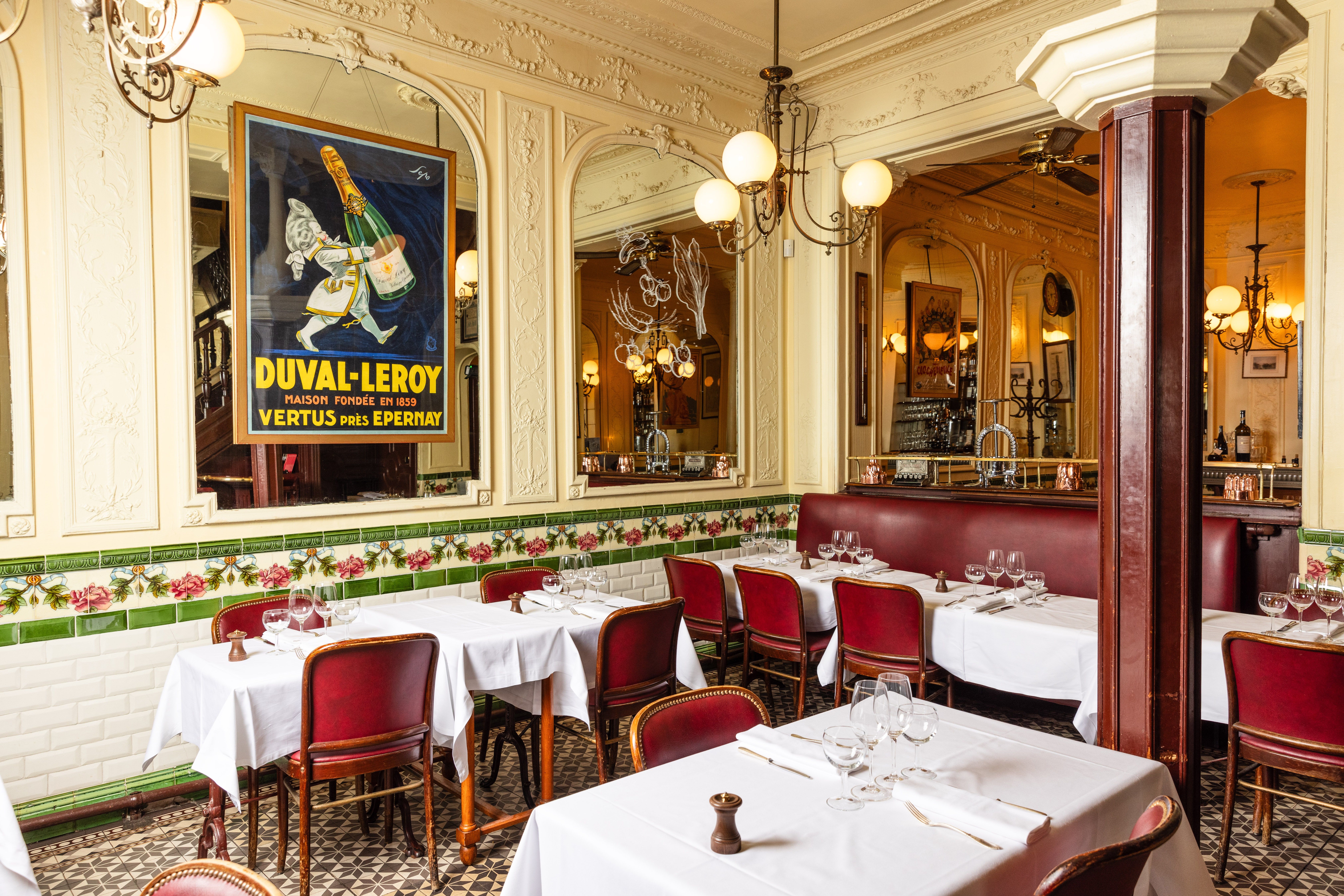 Salle de restaurant parisien aux banquettes rouges et fresques
