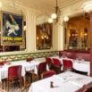 Salle de restaurant parisien aux banquettes rouges et fresques