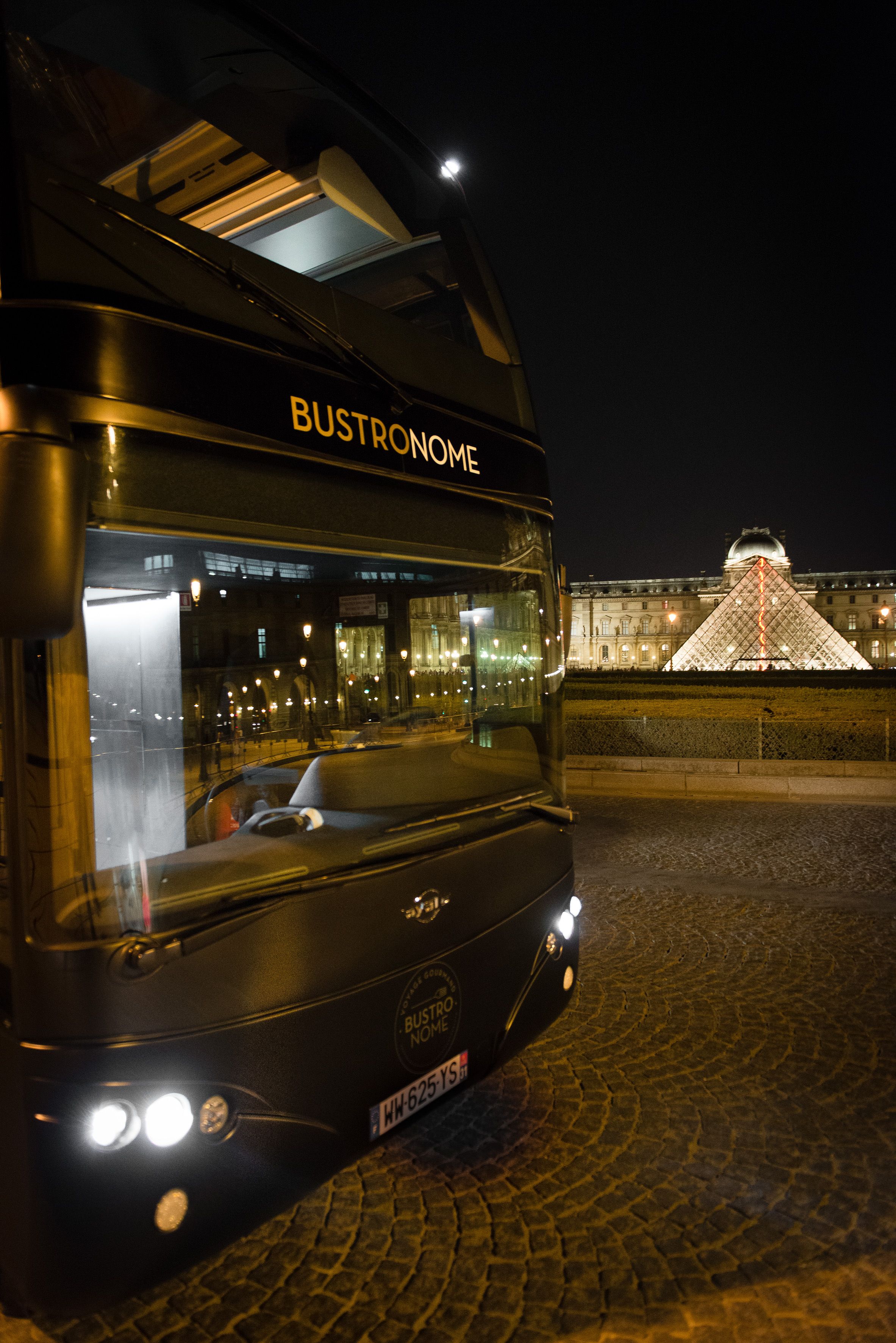 Bus Bustronome de nuit devant la pyramide du Louvre