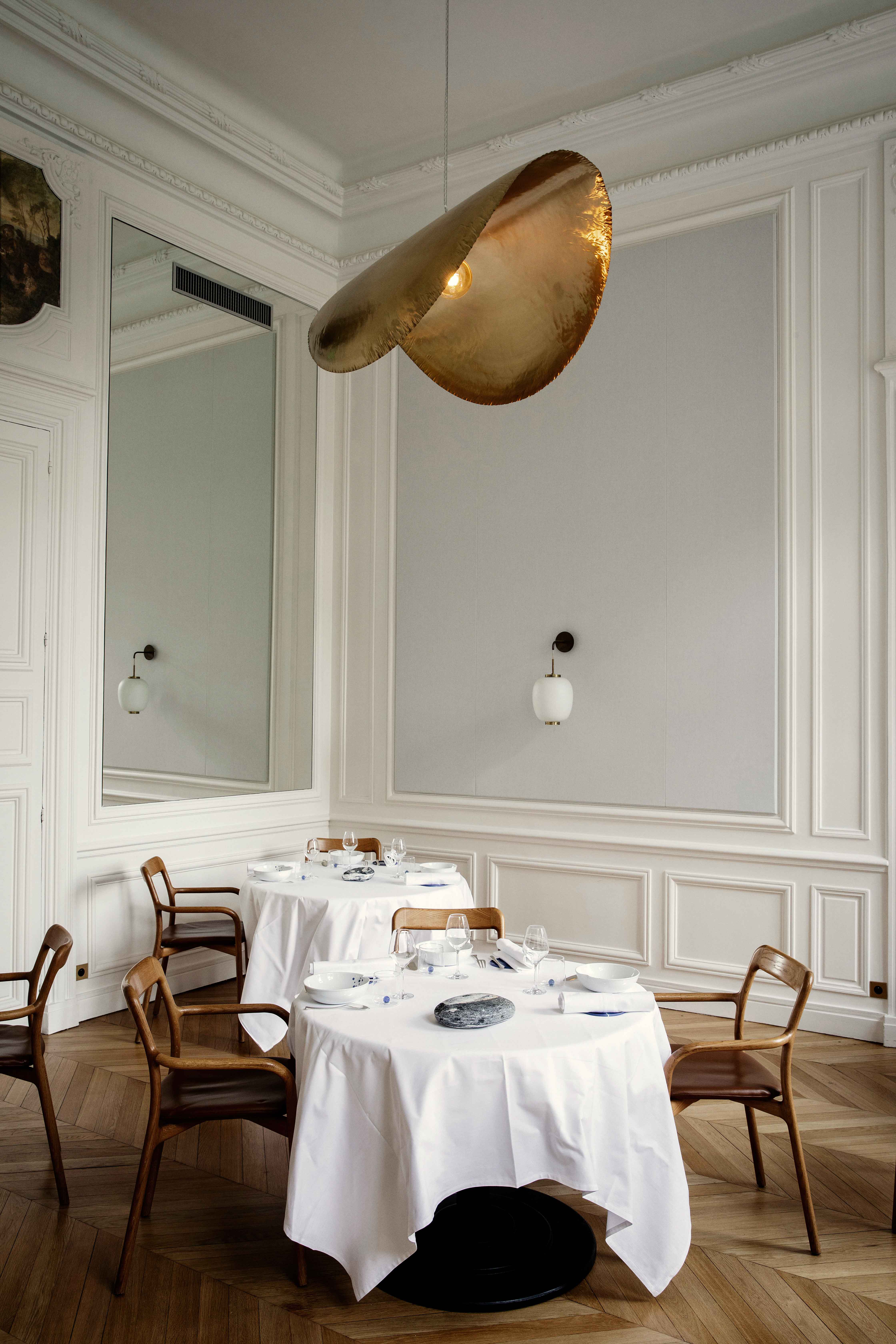 Salle haussmannienne épurée avec luminaire suspendu doré