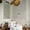 Salle haussmannienne épurée avec luminaire suspendu doré