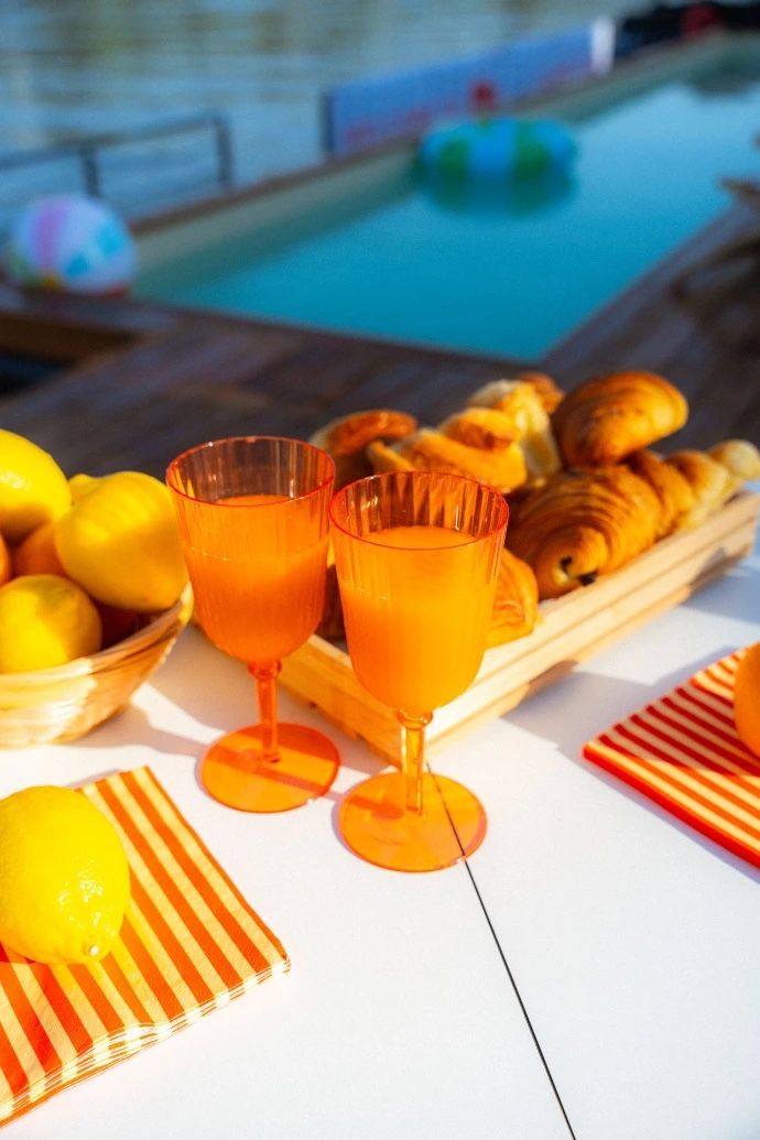 Petit-déjeuner avec viennoiseries et jus d'orange au bord d'une piscine