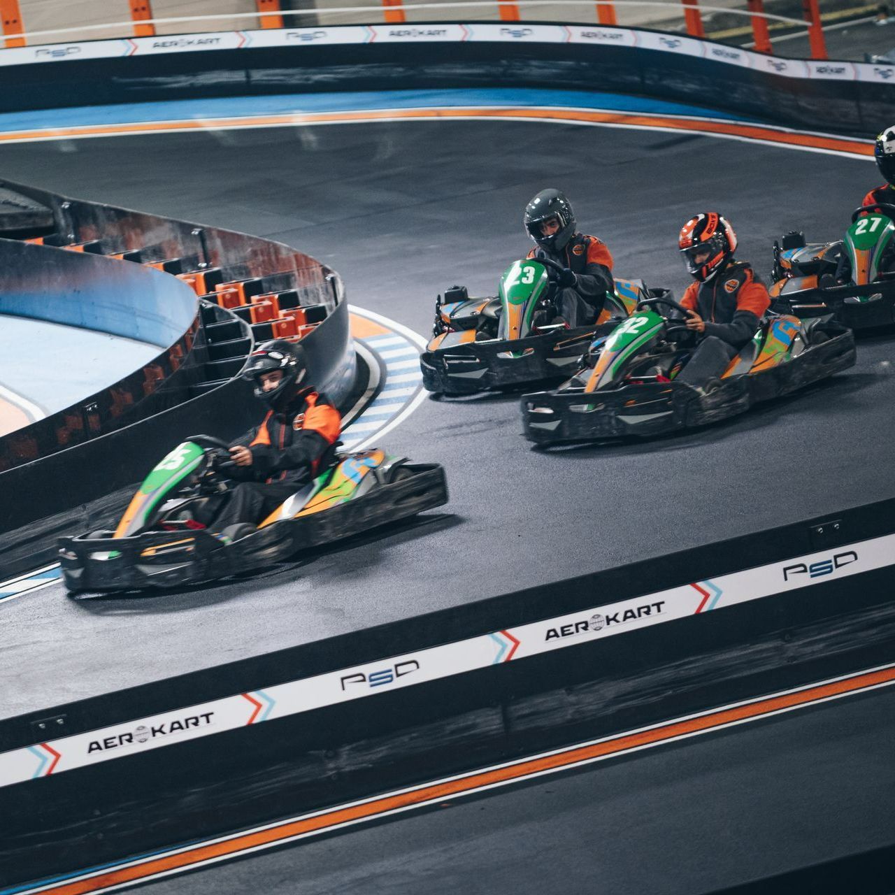 Pilotes de karting indoor en pleine course sur piste relevée