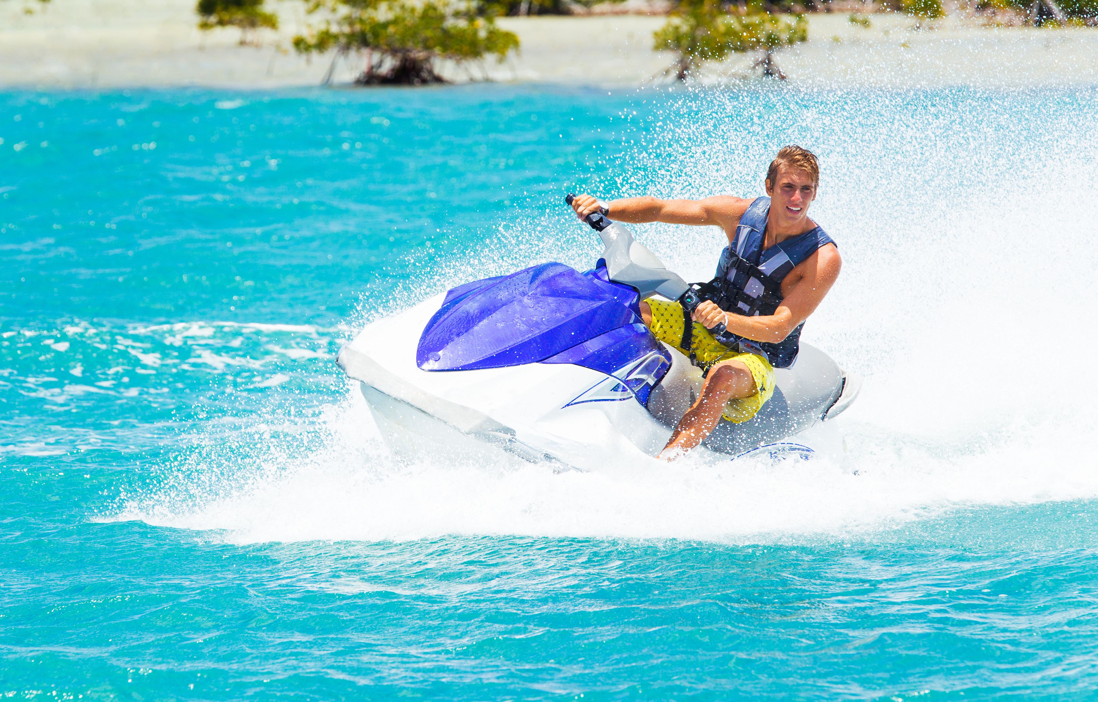 Pilote de jet-ski éclaboussant sur lagon turquoise tropical