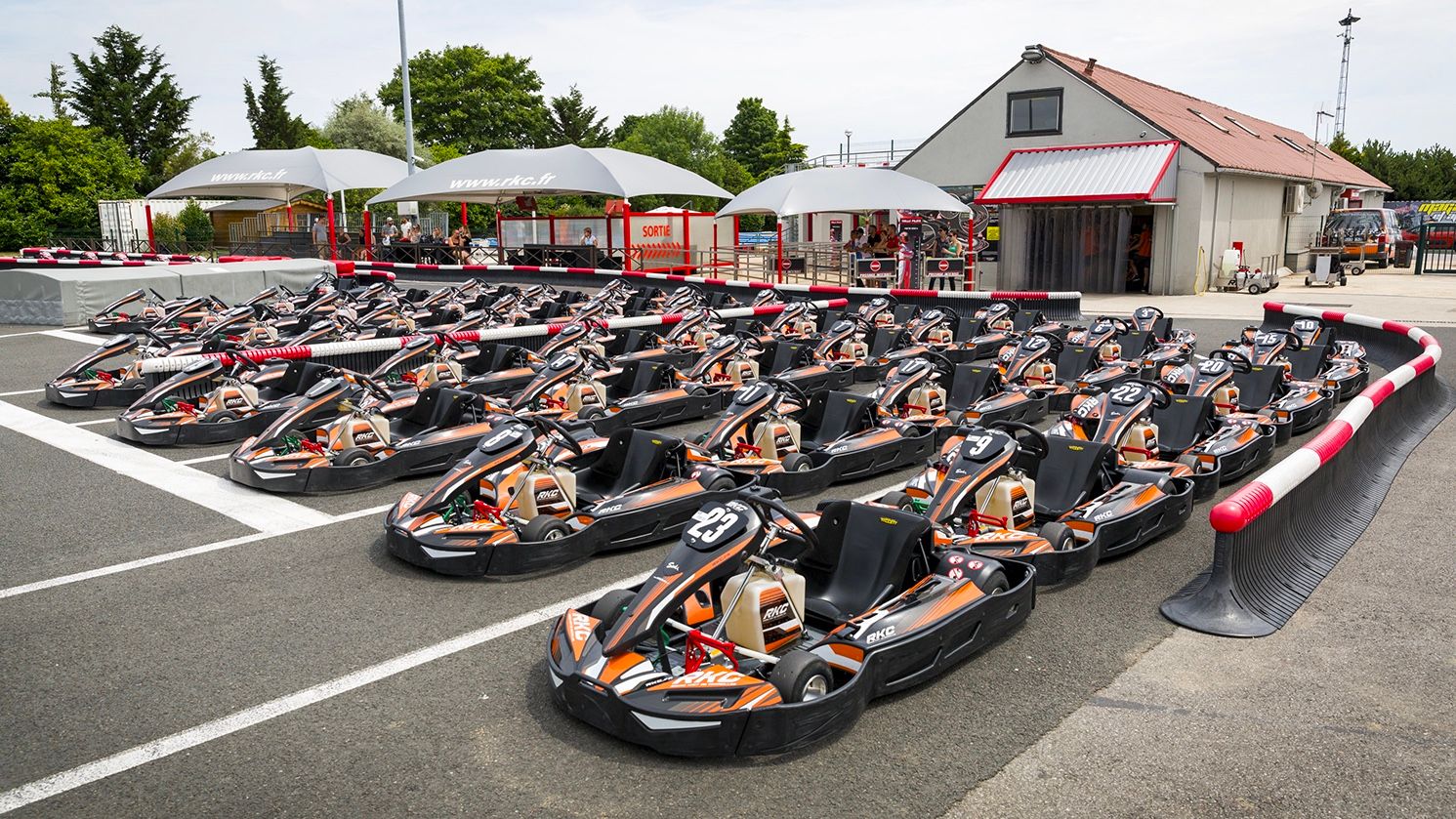Flotte de karts alignés devant le hangar du circuit