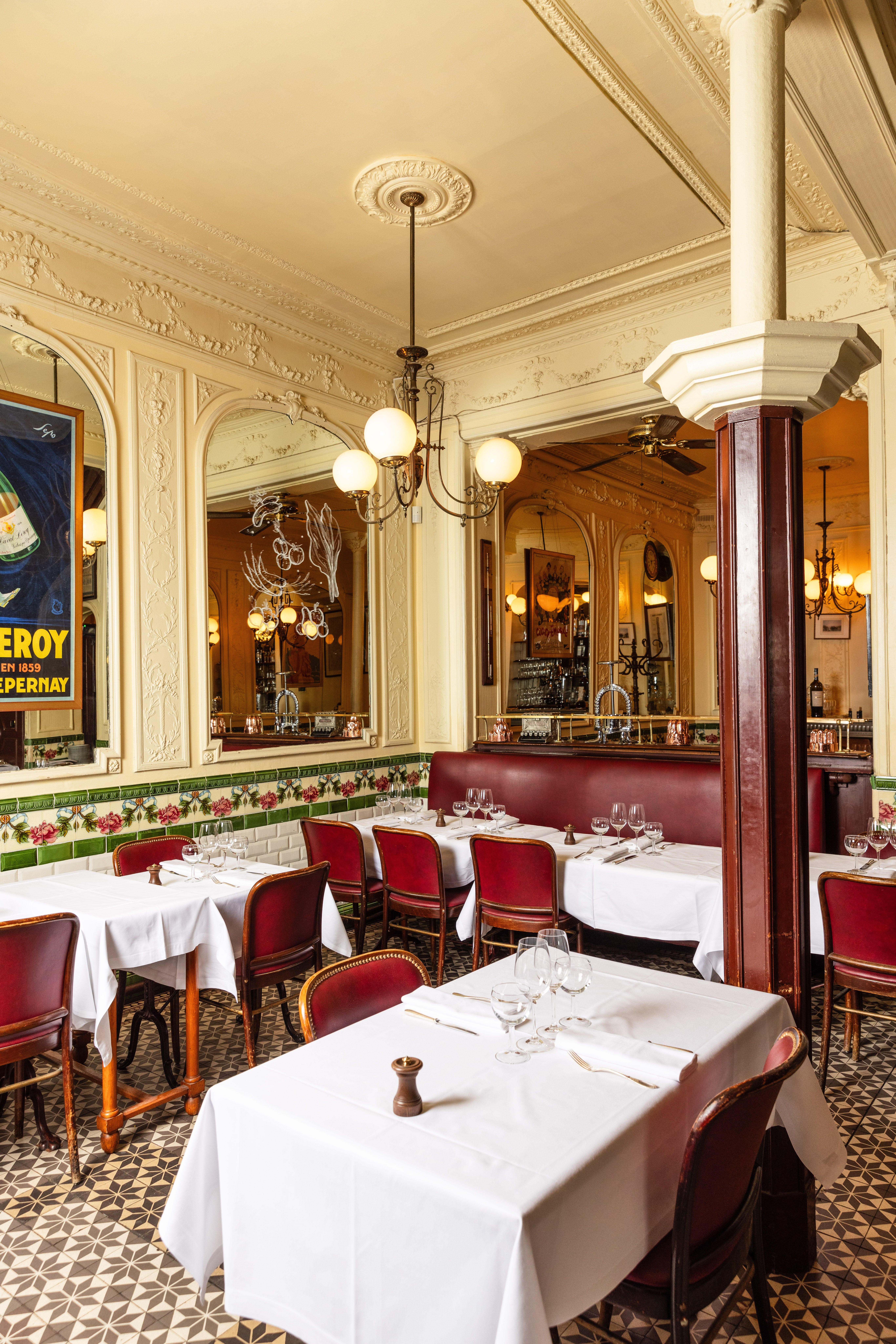 Salle de bistrot parisien avec moulures, tomettes et banquettes rouges