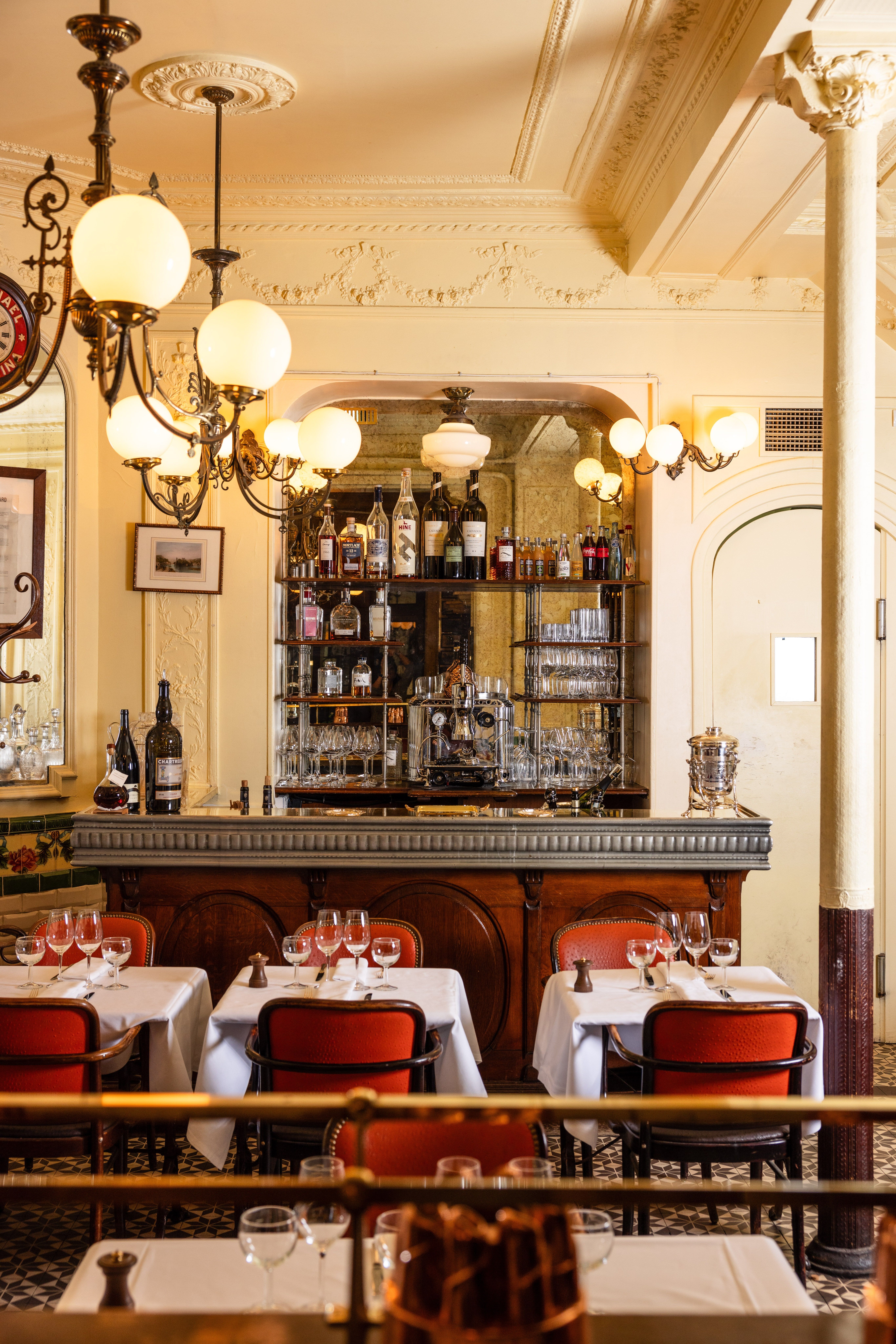 Salle de bistrot parisien aux lustres rétro et bar en miroir