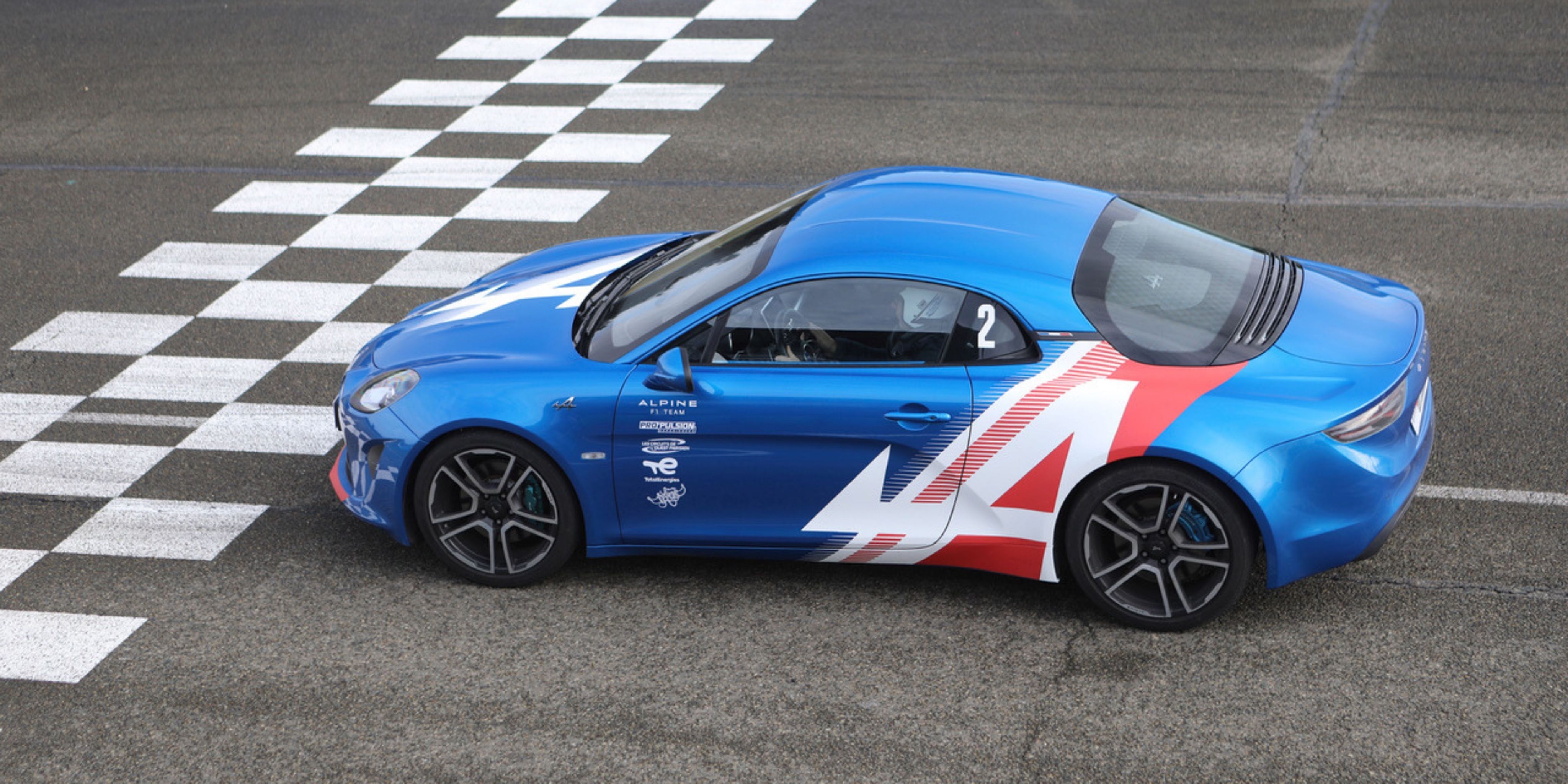 Alpine A110 bleue sur ligne d'arrivée du circuit