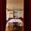 Petite salle de restaurant aperçue entre rideaux rouges