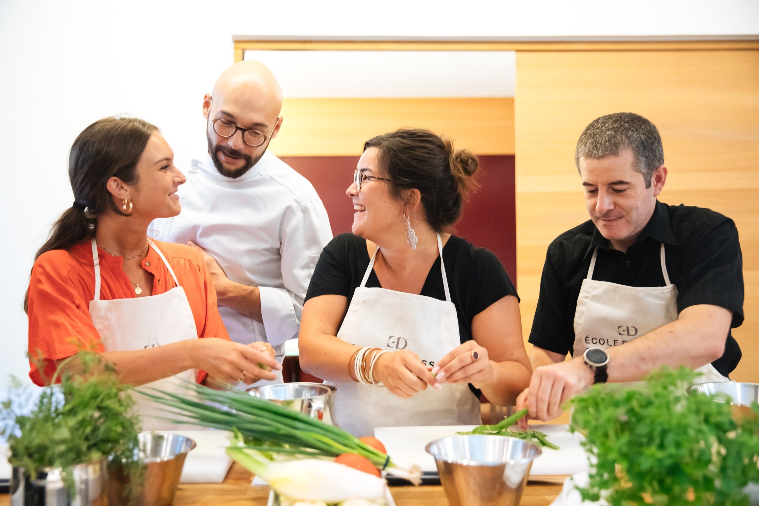 Chef et trois élèves complices en atelier cuisine