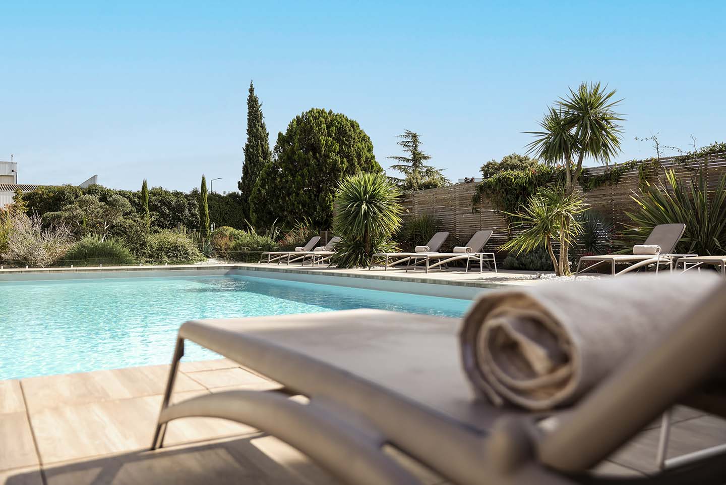Piscine extérieure ensoleillée avec transats et palmiers