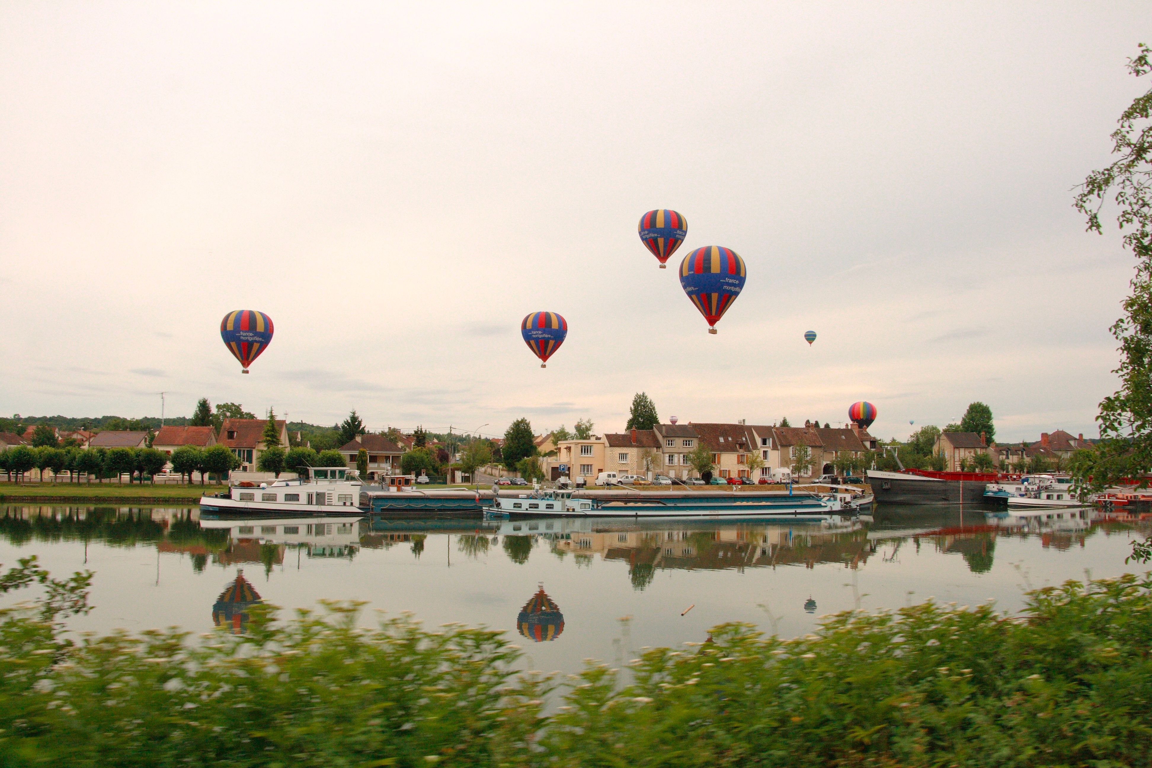 Montgolfières au-dessus d'un village au bord de l'eau