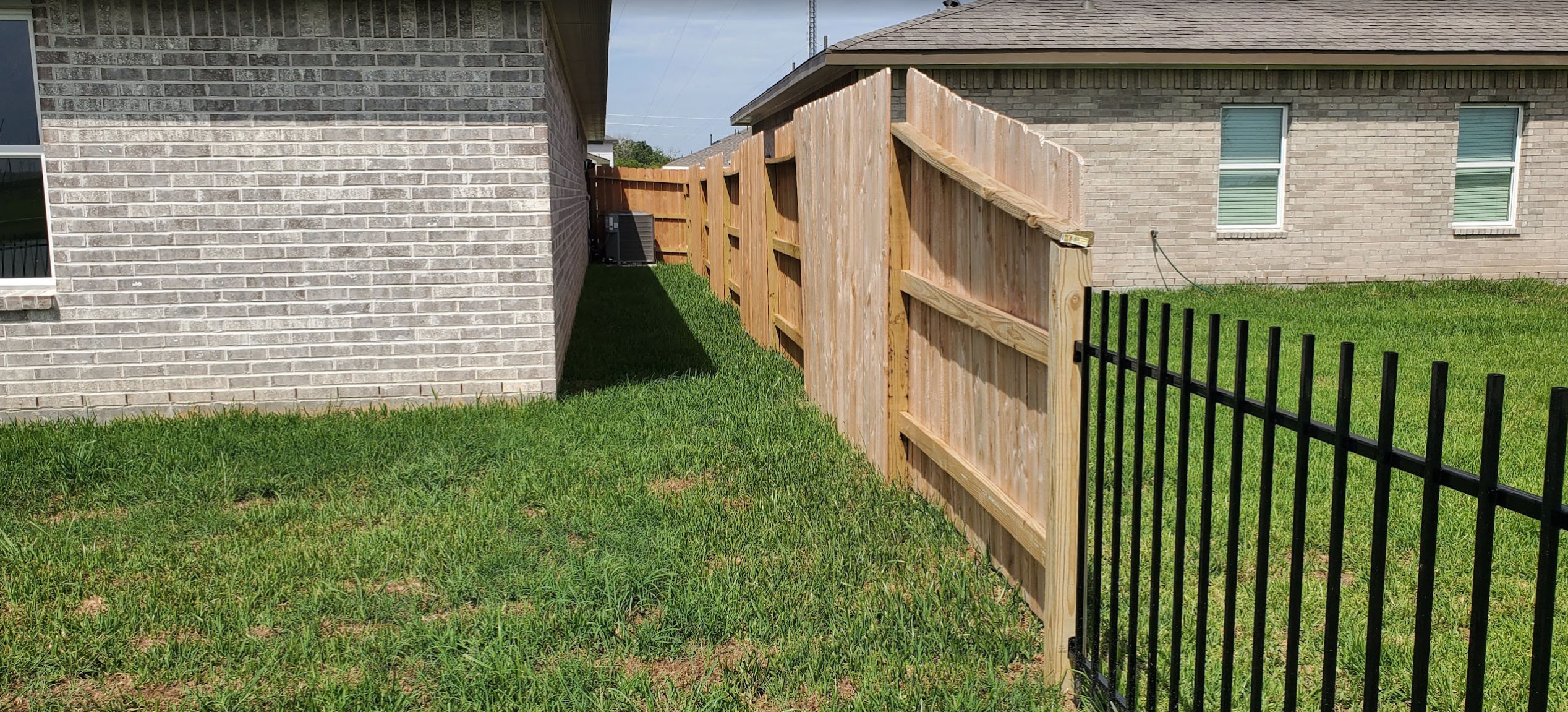 Existing grass side yard between the house and wood fence before paver walkway installation
